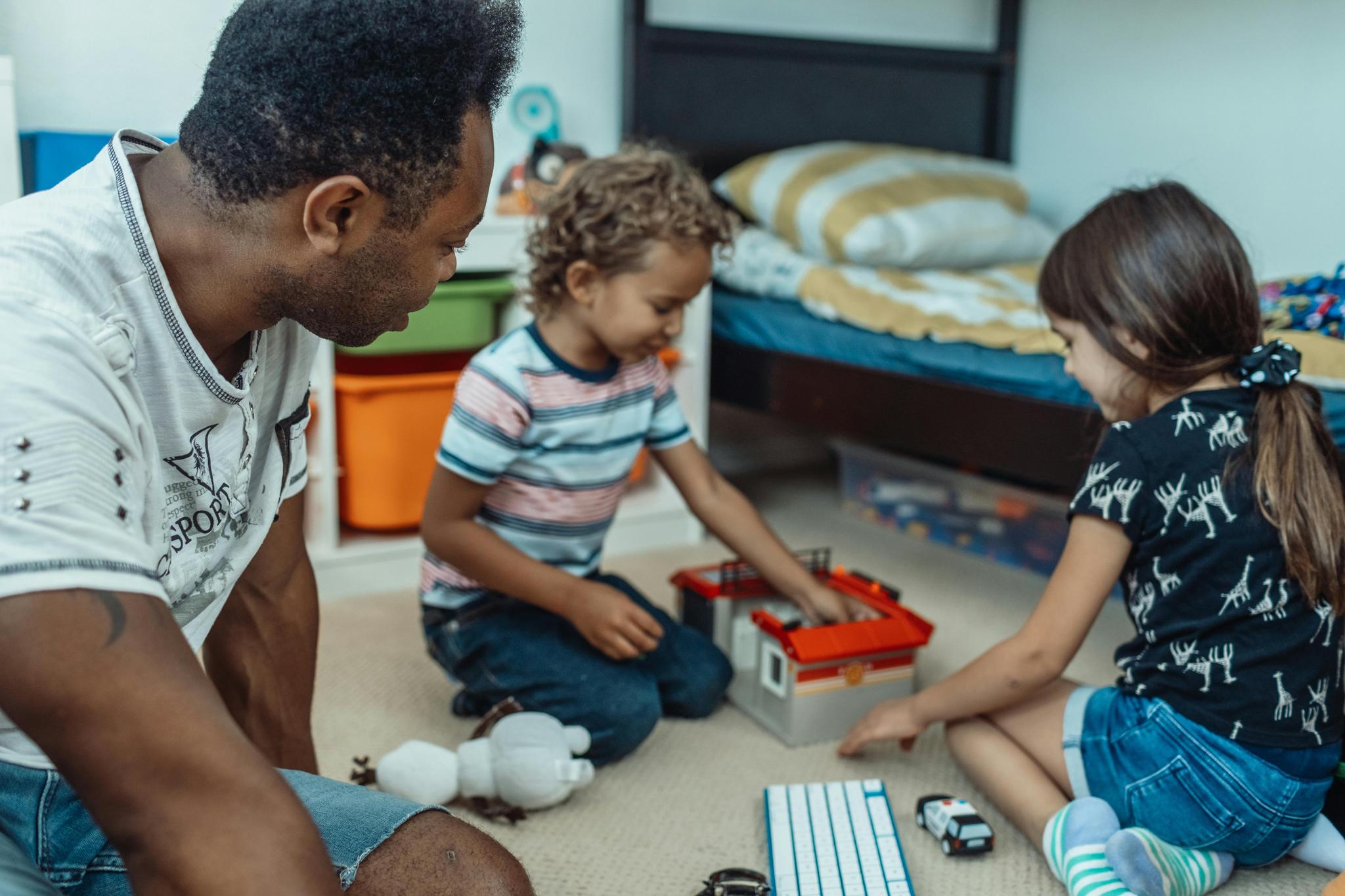 Children in Care, two children playing with a toy while a man looks on
